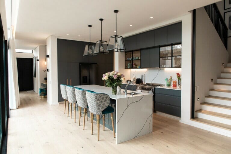 Open-plan kitchen with dark cabinetry and fresh stone countertops